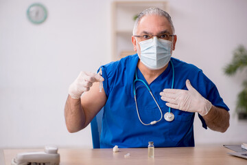 Old male doctor in vaccination concept
