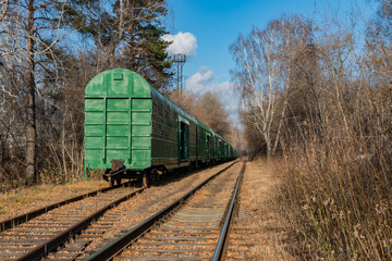 Fototapeta na wymiar Freight cars going into the distance through the forest on the railway