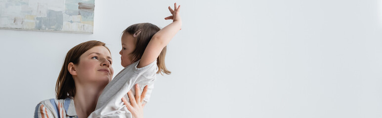 Parent holding daughter with down syndrome at home, banner.