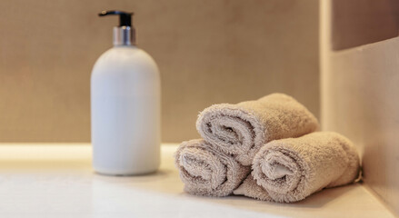 Obraz na płótnie Canvas Bathroom interior detail. Clean hand towels roll ups, soap dispenser and sink basin on a table