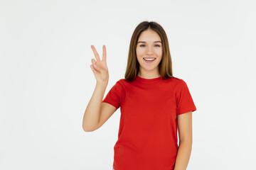 Obraz na płótnie Canvas Funny woman in t-shirt showing peace gestures and her tongue while looking at the camera over white background