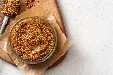 Whole grain mustard in a glass jar close-up.
