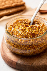 Whole grain mustard in a glass jar close-up.