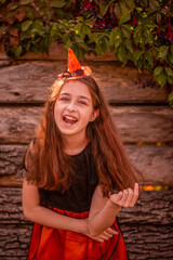 Laughing little girl in a pumpkin costume for halloween. Positive portrait of a teenager.
