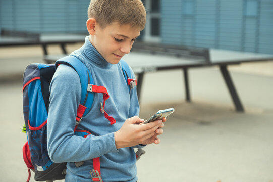 Portrait of teen school boy browsing in internet using cell phone