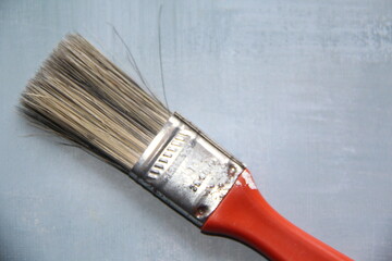 Close-up on the bristles of a red brush isolated on a blue background, top view.