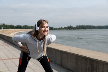 Young happy carefree self-loved and self-aware yoga fitness woman is active and practices yoga outside on a sunny autumn morning. Runner woman stretching muscles outdoor before running sport exercise.