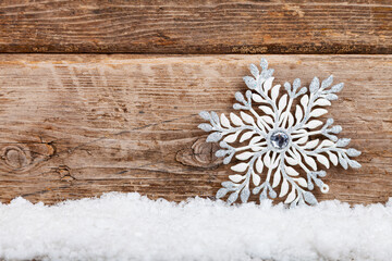 Silvery Christmas snowflakes in the snow on a wooden background.