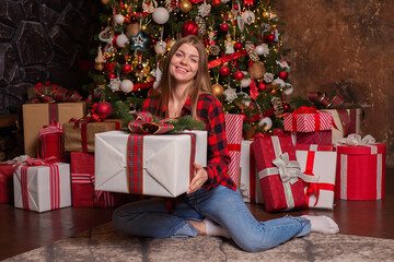 Obraz na płótnie Canvas Young beautiful woman near a christmas tree with gifts in a luxurious interior