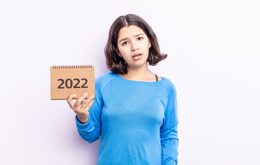 pretty young woman feeling puzzled and confused. 2022 calendar concept
