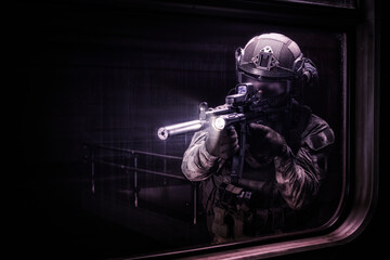 Fighter of the special anti-terrorist unit aims at the window of a railway carriage in the subway. Special operation concept.