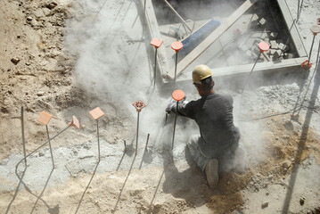 Construction worker grinding concrete slab to flatten