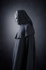 Fototapeta na wymiar Woman ghost in hooded cloak over dark misty background