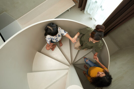 Directly above view of senior Asian woman holding hands of granddaughter and adult daughter on stairs in house