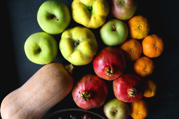 Pan with chestnuts, butternut squash and various fruit on dark background. Flat lay.