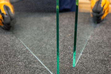 a worker in a glass factory holds two pieces of glass in his hands