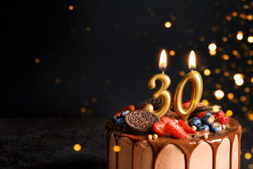 Chocolate birthday cake with berries, cookies and number thirty golden candles on black background,...