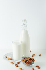 A glass with almond milk and the bowl with almonds