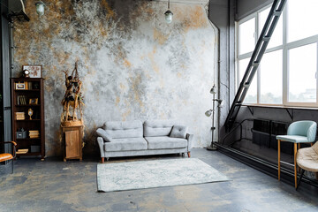 interior shot in the studio. loft studio. a large panoramic window that transmits a lot of light, an unusual decorative wall, A bookcase full of books. a chic gray sofa. Arrangement of furniture.