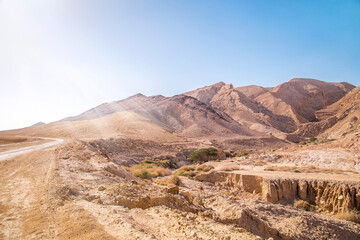 Rocky and dusty mountains of the Negev Desert in Israel. Breathtaking landscape with huge stones on top of the hillside near the peak of mountain range at sunbeam. Summer Landscape view with sunlight.