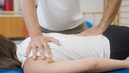 Obraz na płótnie Canvas Physiotherapist's hands doing medical back massage, to a female patient, during a rehabilitation treatment.