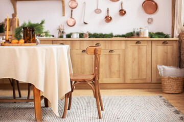 Stylish dining room in rustic style. Cozy Wooden kitchen decorated Christmas or new year. On table fir branche in vase, Xmas cookies. Interior design scandinavian kitchen with round table and chair.	