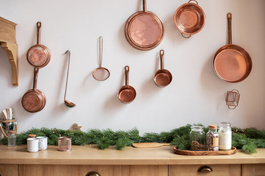 Set of saucepans hanging in kitchen. Hanging Copper kitchen utensil on the white wall. Different kind of vintage copper cookware, pans, pots and funnel on wooden kitchen. Rustic kitchen interior decor - Powered by Adobe