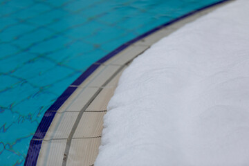 Obraz na płótnie Canvas An outdoor swimming pool with blue water/tiles and snow on the side