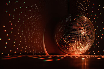 Disco ball reflecting burnt orange color light in a dark hall for discos. Holidays concept. Copy space.	