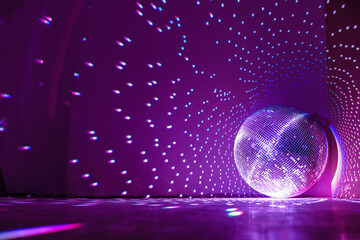 Disco ball reflecting purple light in a dark hall for discos. Holidays concept. Copy space.	