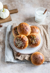Fresh homemade pumpkin buns with brown sugar or seeds, light concrete background. Autumn bakery.