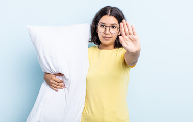 pretty young woman looking serious showing open palm making stop gesture. bed concept