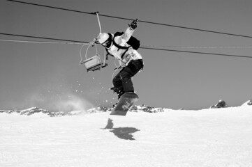 Snowboarder jumping on snowy ski slope. Black and white retro toned image.
