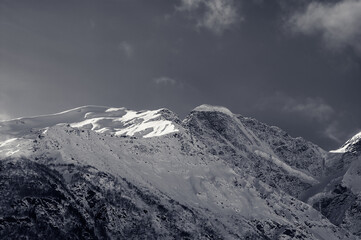 Black and white snowy sunlight mountains, view from off piste slope
