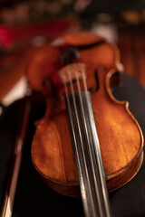 A violin or a viola on a black chair. A classical string instrument common to symphony orchestra.