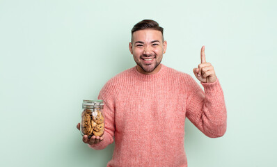 young handsome man feeling like a happy and excited genius after realizing an idea. cookies bottle...