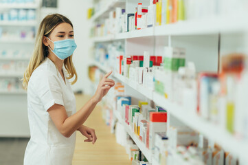 Pharmacist wearing protective mask and choosing medicine in pharmacy store