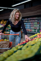 Woman in a supermarket holding shopping cart while grocery shopping