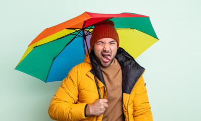 young handsome man with cheerful and rebellious attitude, joking and sticking tongue out. rain and...