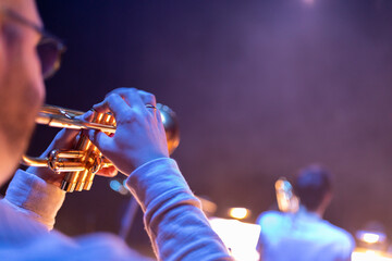 A trumpet player playing the trumpet in a jazz concert with colorful stage lights and smoke