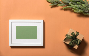 White frame with green background for the inscription. Branches with green needles are decorated with a red star. The box is decorated with a bow. Christmas background for an inscription.