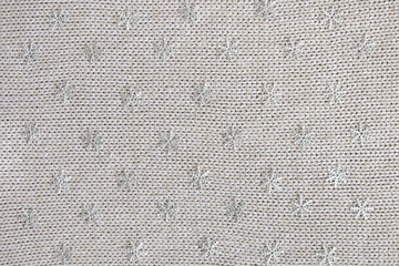 knitted background with snowflakes. Knitted fabric with sequins with snowflakes.
