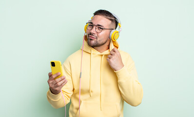 young handsome man looking arrogant, successful, positive and proud. headphones and smartphone...