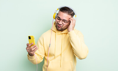 young handsome man feeling bored, frustrated and sleepy after a tiresome. headphones and smartphone...