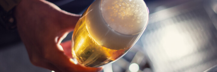 glass of craft beer in bartender hand closeup panorama - obrazy, fototapety, plakaty