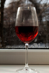 A glass of wine on the windowsill. Winter weather outside the window