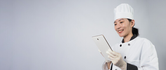 Asian woman chef holding smartphone or digital tablet and received order from online shop or...