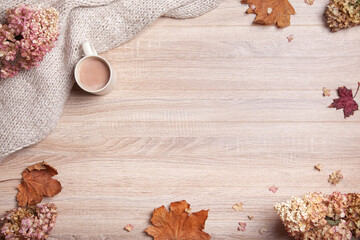 Autumn, fall leaves, hot chocolate and knitted plaid, on a wooden table background. Relaxing, cozy and still life concept. Top view, flat lay, copy space