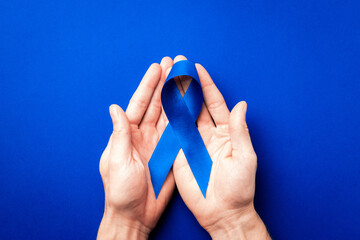 Blue ribbon cancer. Awareness prostate cancer of men health in November. Blue ribbon in hands...