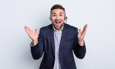 young handsome man feeling happy and astonished at something unbelievable. telearketer concept
